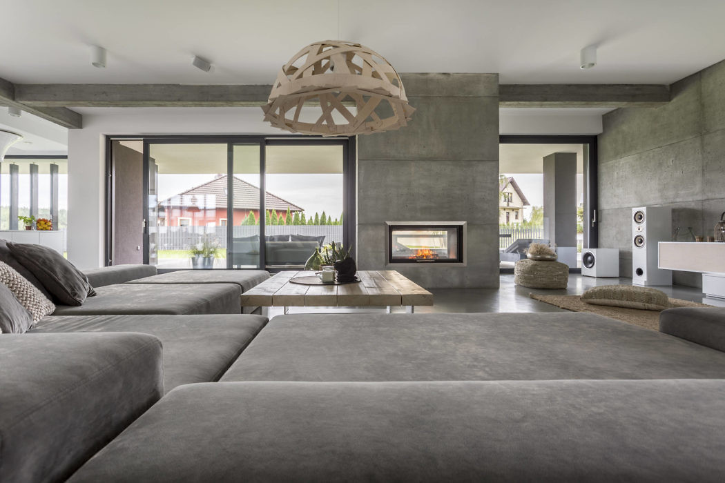 Modern living room with large sofas, fireplace, and concrete finishes.