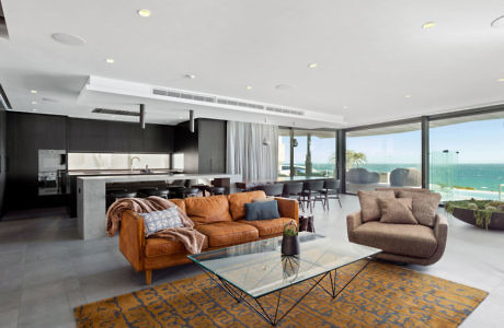 Modern living room with ocean view, plush sofas, and glass table.