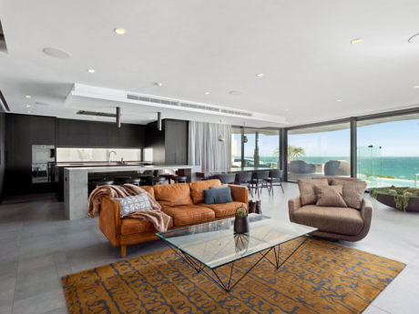 Modern living room with ocean view, plush sofas, and glass table.