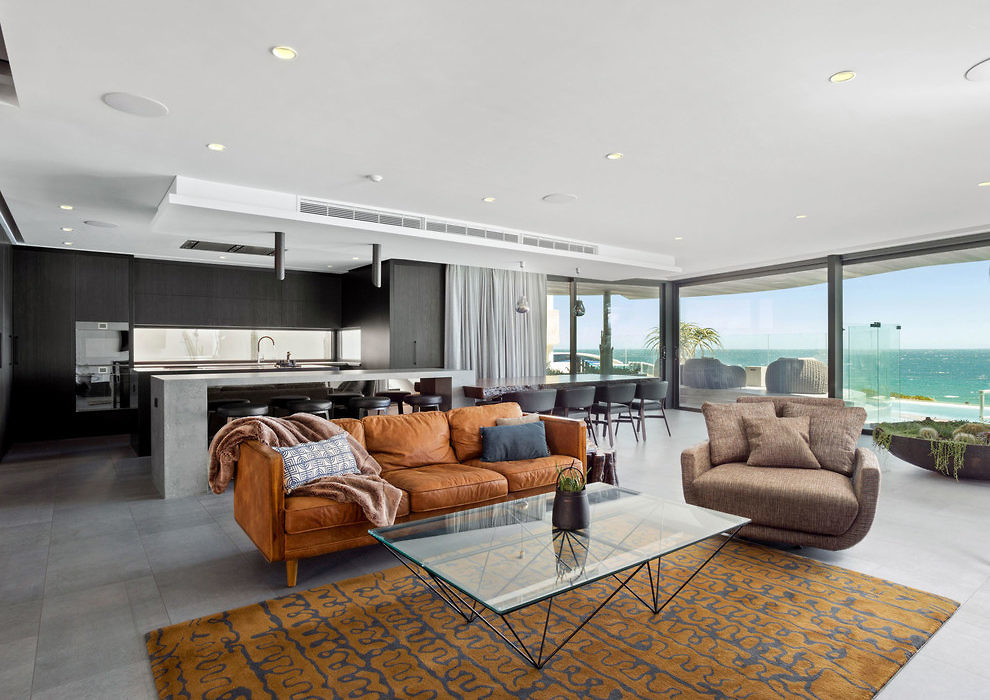Modern living room with ocean view, plush sofas, and glass table.