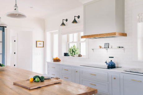 Bright modern kitchen with white cabinets, wooden countertops, and a kettle on the stove
