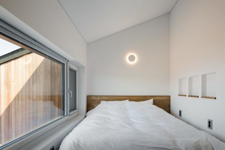 Minimalist bedroom with large window and circular ceiling light.