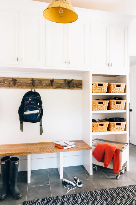 Bright mudroom with built-in bench, storage baskets, and pendant light.