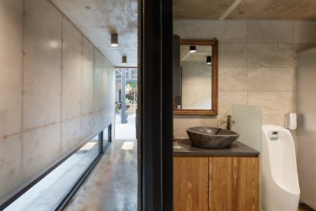 Modern bathroom with wooden vanity, concrete walls, and large window.