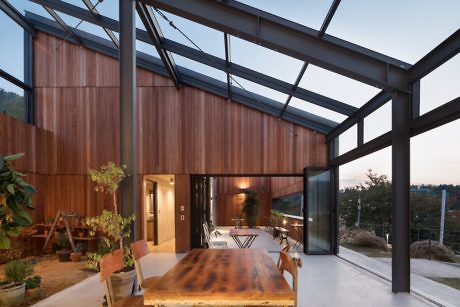 Modern room with large glass ceiling and wooden walls, featuring a dining table.