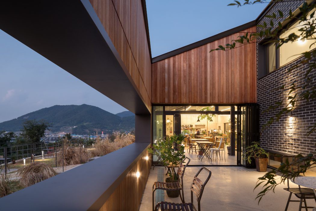 Contemporary wooden and brick home with outdoor seating overlooking mountains at dusk.