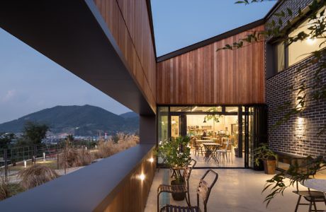 Contemporary wooden and brick home with outdoor seating overlooking mountains at dusk.