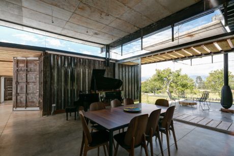Contemporary dining area with piano and glass walls overlooking a garden.