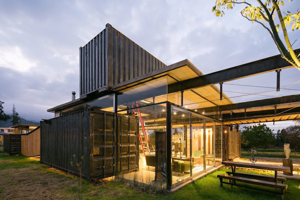 Shipping container home with glass facade at dusk.