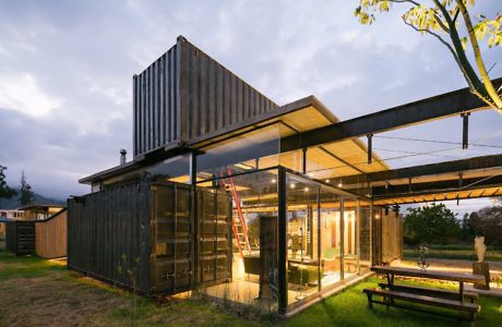 Shipping container home with glass facade at dusk.