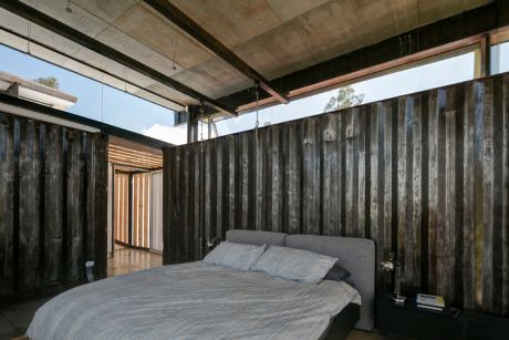 Minimalist bedroom with concrete ceiling, wooden walls, and queen-size bed.