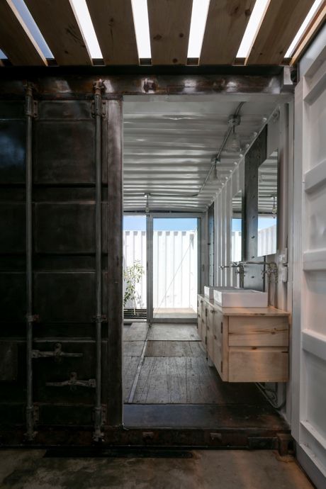 Interior of a converted shipping container with modern fixtures and wooden floor.