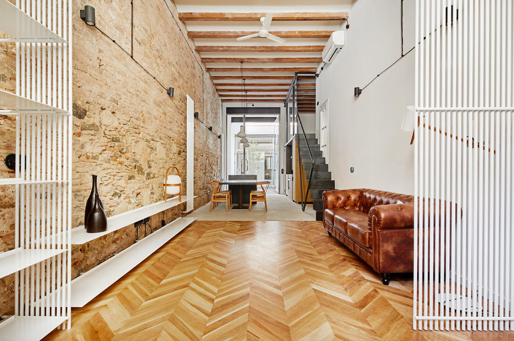 Modern interior with exposed brick, herringbone floor, and minimalist decor.