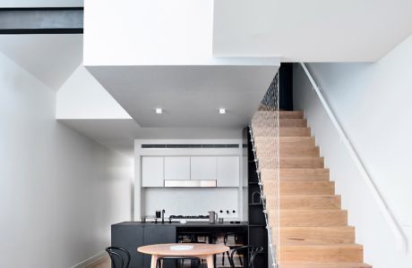 Contemporary home interior with a wooden staircase and sleek kitchen.