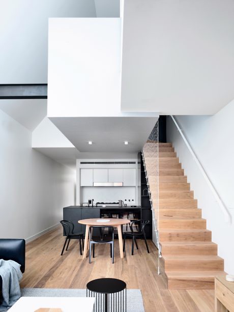 Contemporary home interior with a wooden staircase and sleek kitchen.