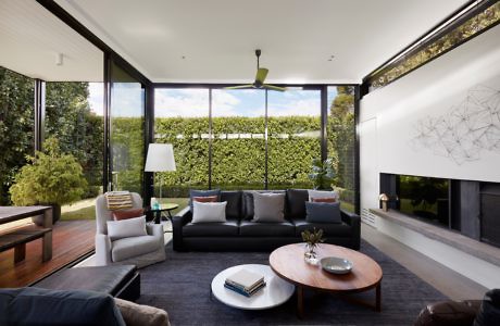 Modern living room with large windows and a hedge view.