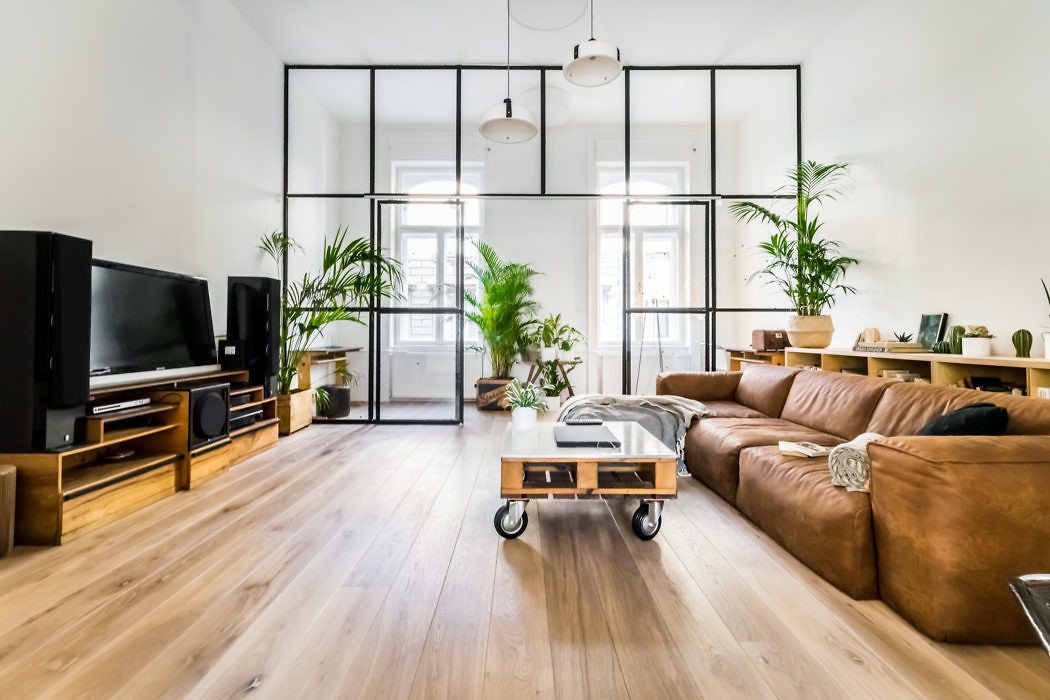 Modern living room with glass partition, leather sofa, and wooden floor.