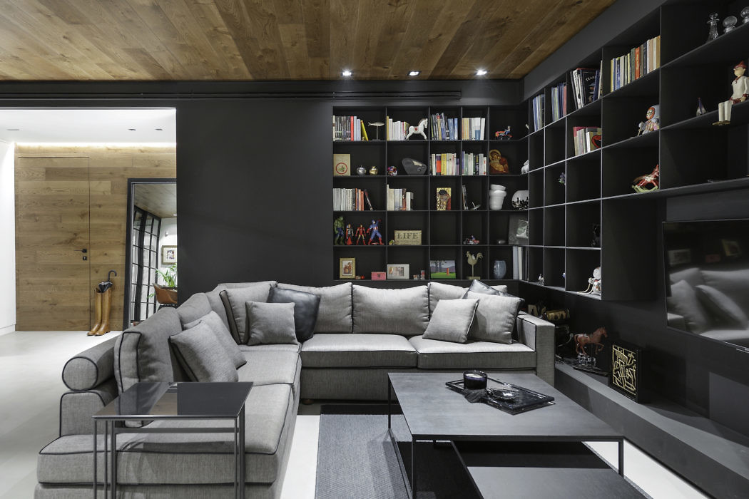 Modern living room with large gray sectional sofa and black bookshelf.
