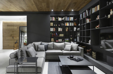 Modern living room with large gray sectional sofa and black bookshelf.