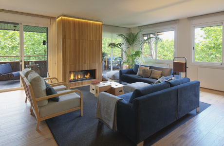 Modern living room with blue sofas, a fireplace, and large windows.