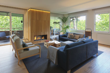 Modern living room with blue sofas, a fireplace, and large windows.