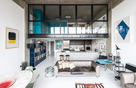 Contemporary loft with mezzanine, industrial finishes, and colorful art.