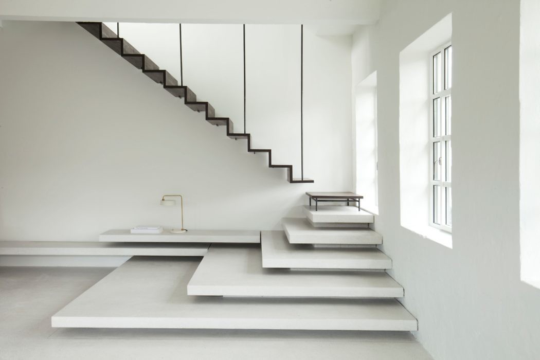 Minimalist interior with white walls and floating staircase.