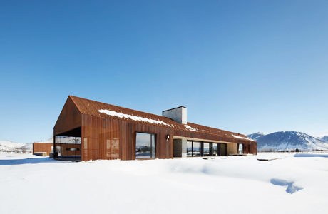 Modern house with rusted steel exterior in a snowy landscape.