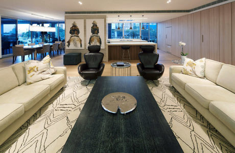 Modern living room with beige sofas, dark tables, and cityscape view.