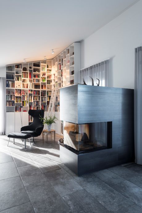 Contemporary living space with a metallic fireplace and a bookshelf-lined wall.