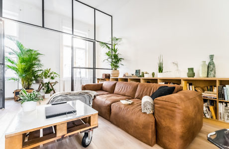 Modern living room with a large brown sofa and glass coffee table.