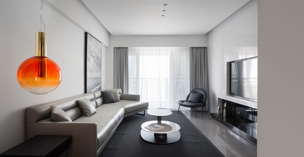 Modern living room with a gray sofa, round tables, large window, and an
