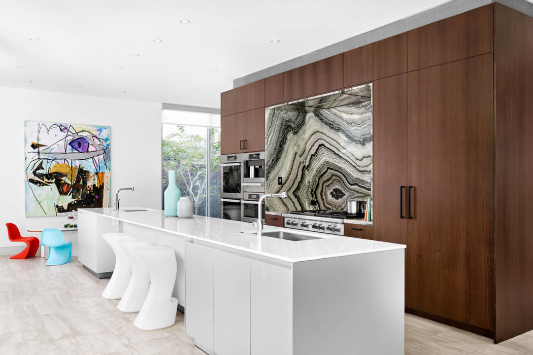 Modern kitchen interior with white island, wooden cabinets, and abstract art.