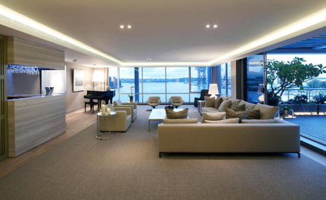 Modern living room interior with sofas, indirect lighting, and a view of the waterfront