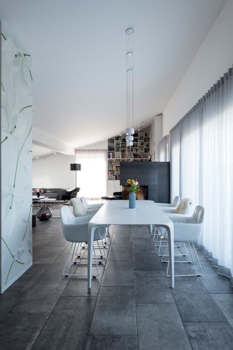 Modern dining room with white furniture and gray tiled floor, natural light from large windows