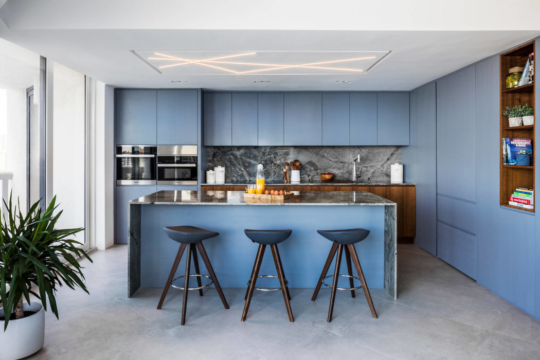 Modern kitchen with blue cabinets, island, and bar stools.