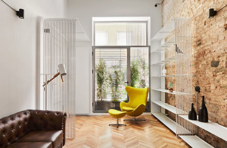 Chic interior with exposed brick, vibrant yellow chair, and chesterfield sofa