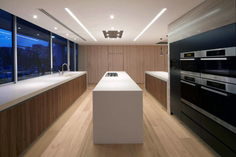 Sleek kitchen with wood accents, integrated appliances, and LED lighting.