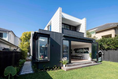 Modern two-story house with black and white exterior and open patio.