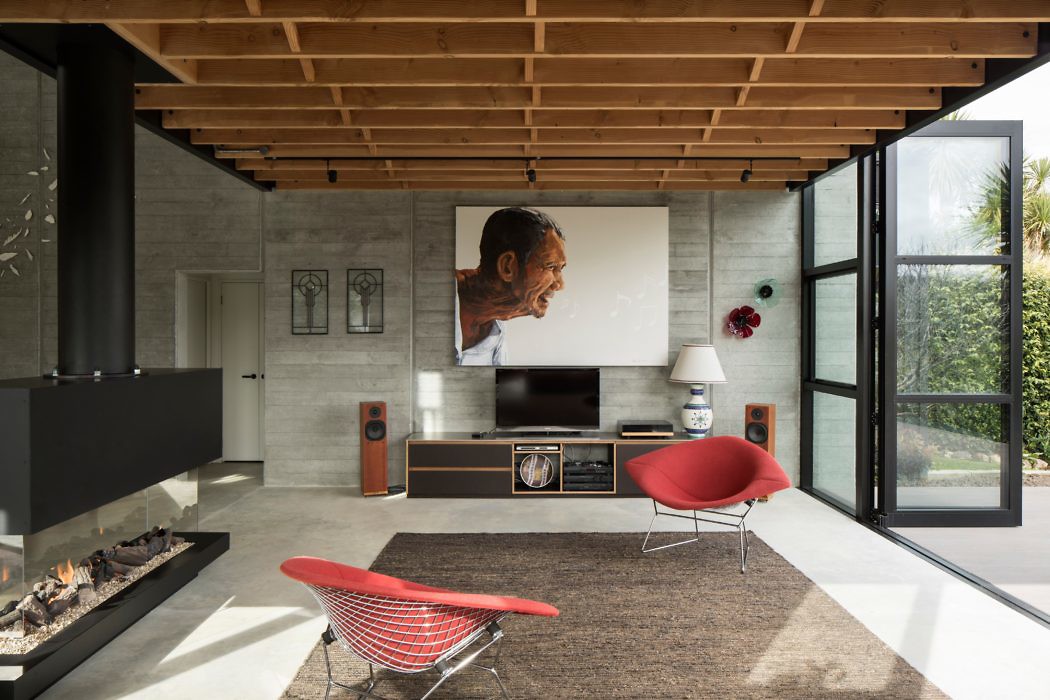 Modern living room with fireplace, red chair, and large portrait over TV.