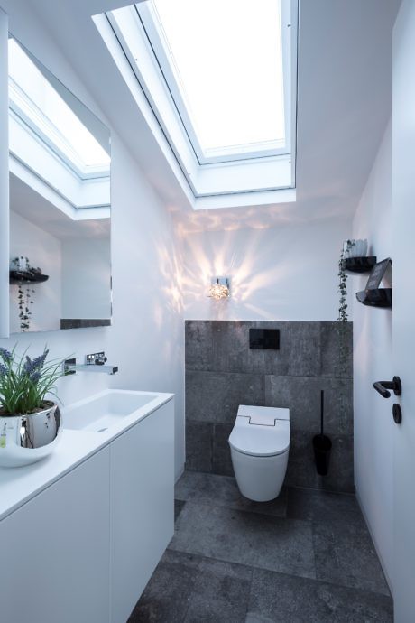 Modern bathroom with skylights and a mix of white and gray finishes.