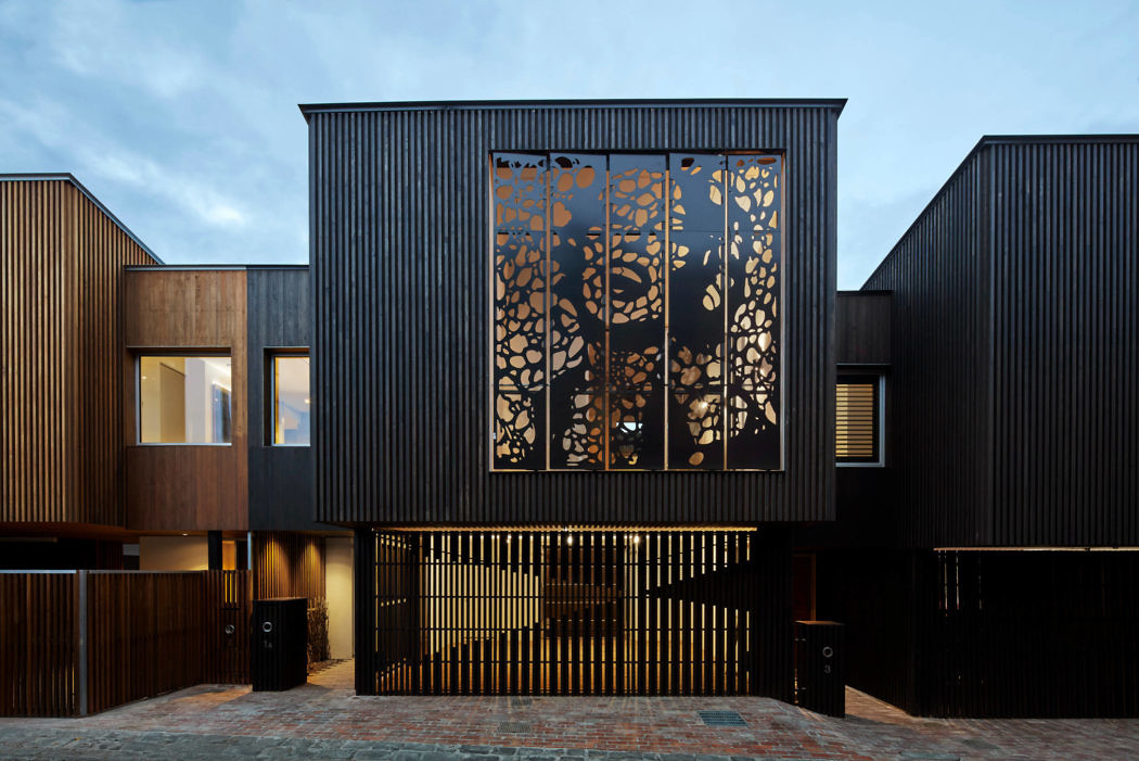 Modern house exterior with decorative metal screen and wooden cladding.