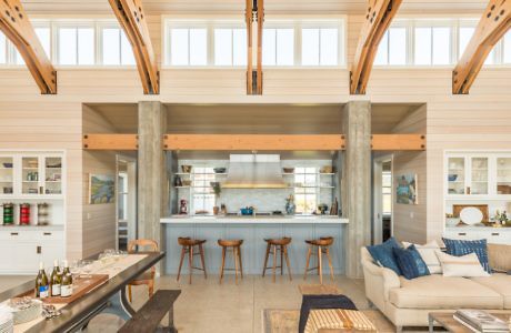 Modern kitchen in an open-plan living space with high ceilings and wooden details.