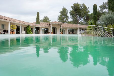 Single-story home with large pool and verdant landscaping.