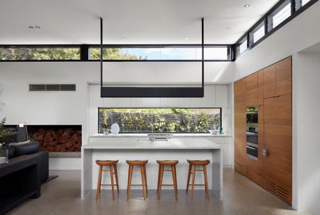 Modern kitchen interior with white island and wooden stools.