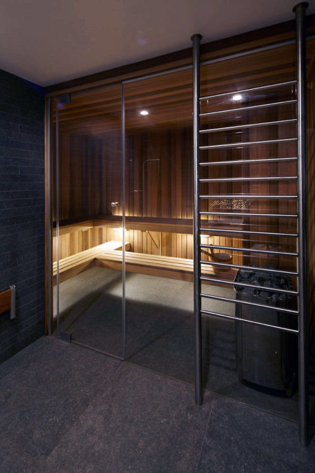 Modern sauna room with wooden benches and glass door.
