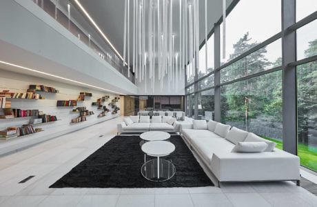 Modern living room with white sofa, floor-to-ceiling windows, and hanging lights