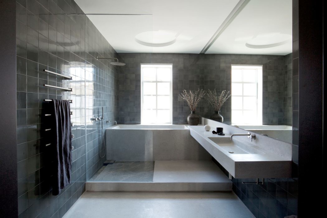 Minimalist bathroom with gray tiles, built-in bathtub, and skylights.