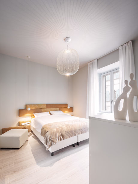Minimalist white bedroom with sleek furniture and pendant light.