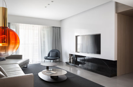 Modern living room with minimalist decor and large orange pendant light.